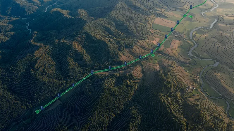 Aerial terrain view with a geospatial mapping data overlay showing a transmission corridor route